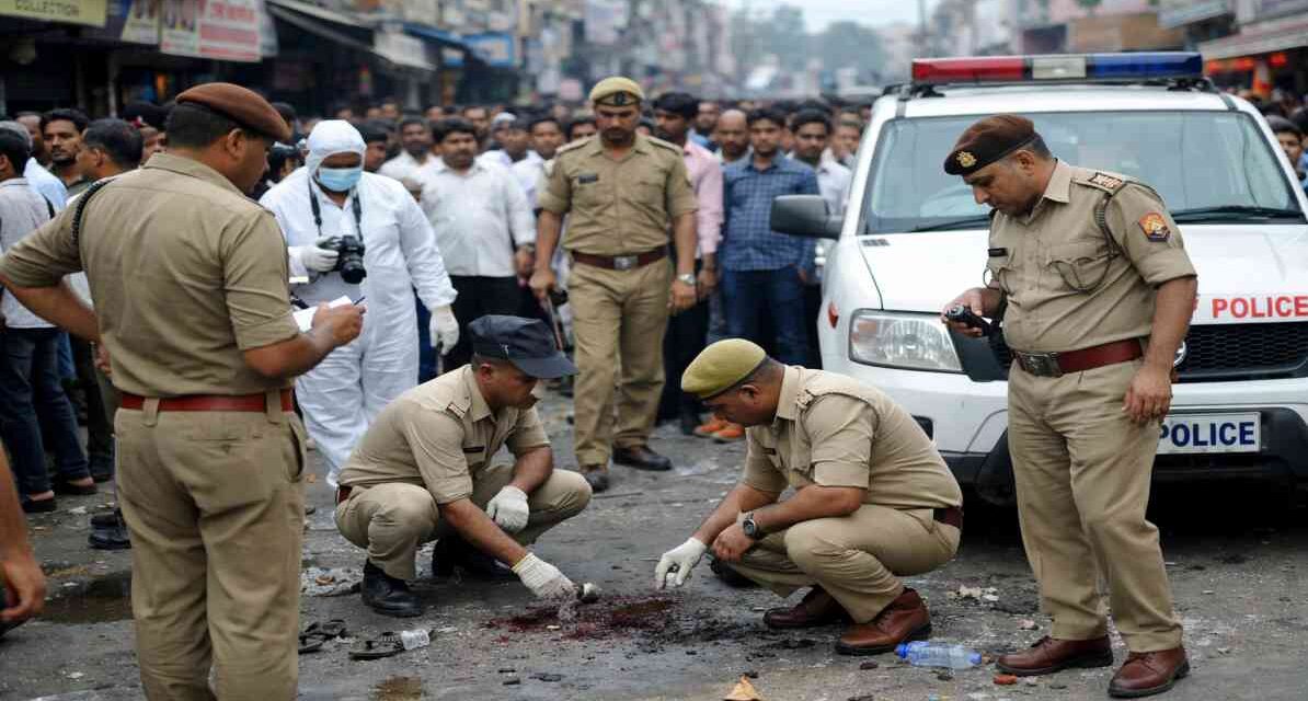 मेरठ की सड़क पर फायरिंग के बाद जांच करती पुलिस और जुटी भीड़ का दृश्य।