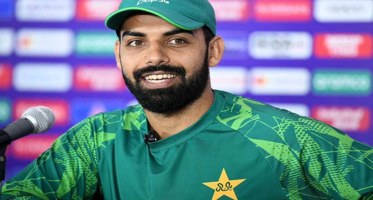 शादाब खान प्रेस कॉन्फ्रेंस में मीडिया से बातचीत करते हुए, साथ में PCB का लोगो और पाकिस्तान टीम की झलक।