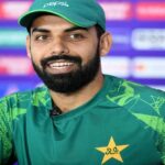 शादाब खान प्रेस कॉन्फ्रेंस में मीडिया से बातचीत करते हुए, साथ में PCB का लोगो और पाकिस्तान टीम की झलक।